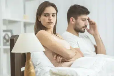 Woman and man sitting in bed looking annoyed