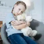 Sad girl hugging teddy bear