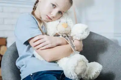 Sad girl hugging teddy bear