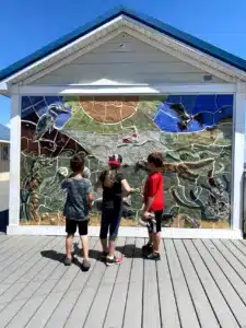 Three kids observing a mural