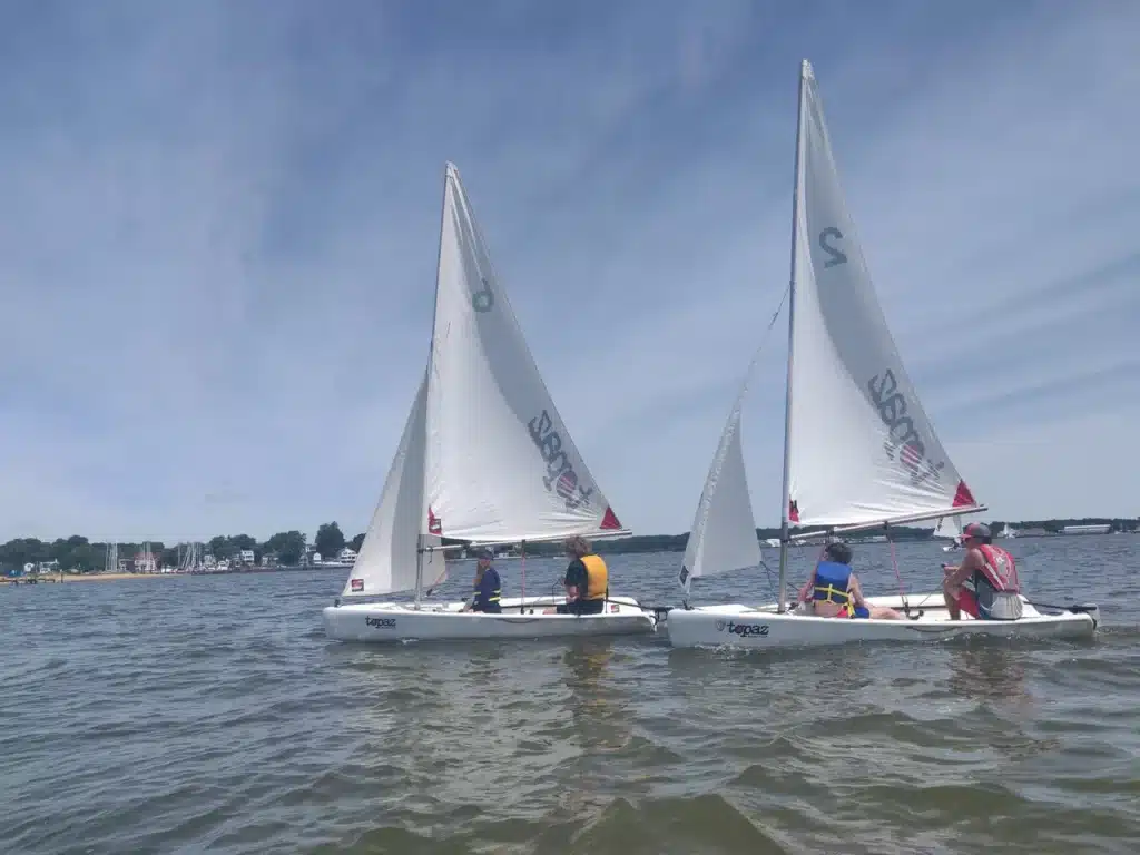 Two sailboats with people on the water