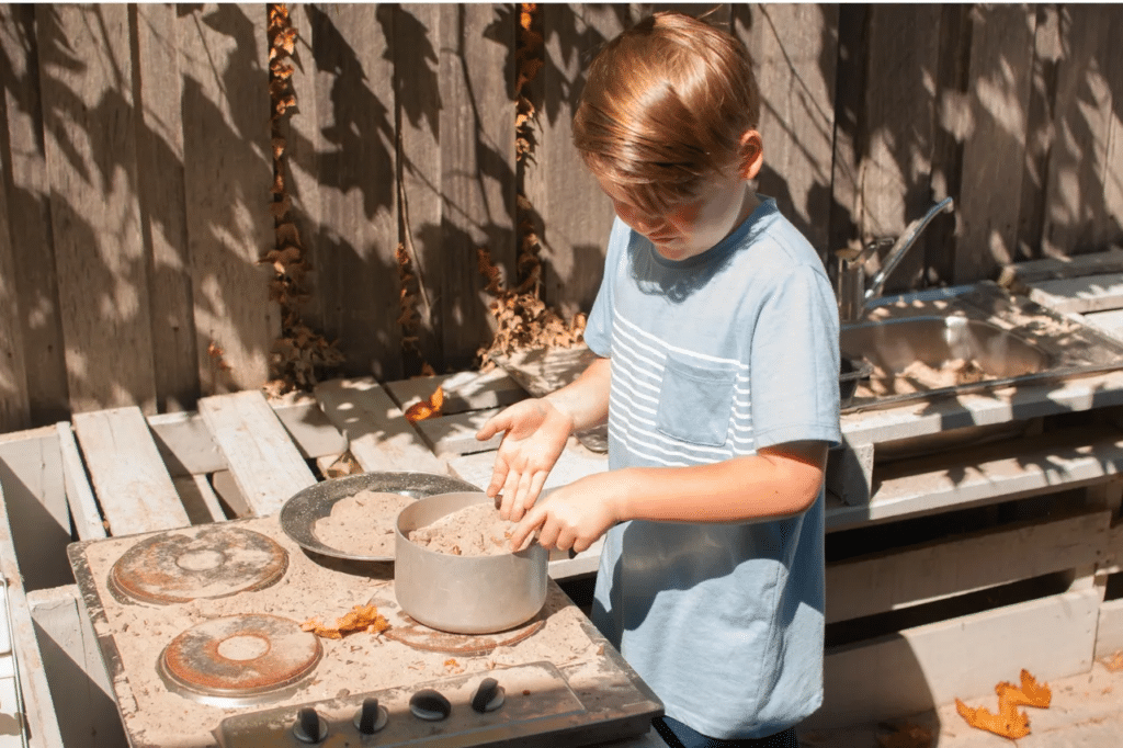 Young boy playing in his mud kitchen