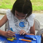 Girl coloring suncatcher outside