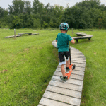 boy riding scooter on boardwalk