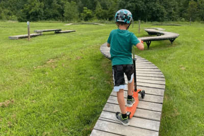 boy riding scooter on boardwalk