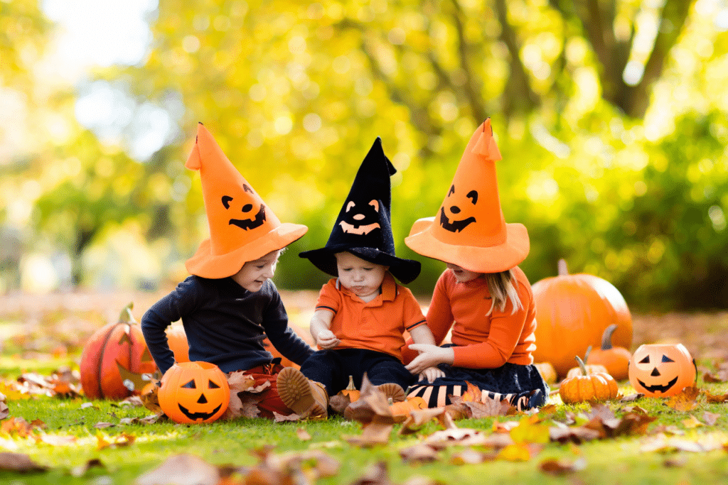 Three kids in Halloween costumes sitting on the grass