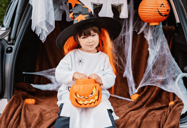 kid dressed as a witch with jack o' lantern