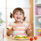 Toddler smiling and eating her veggies