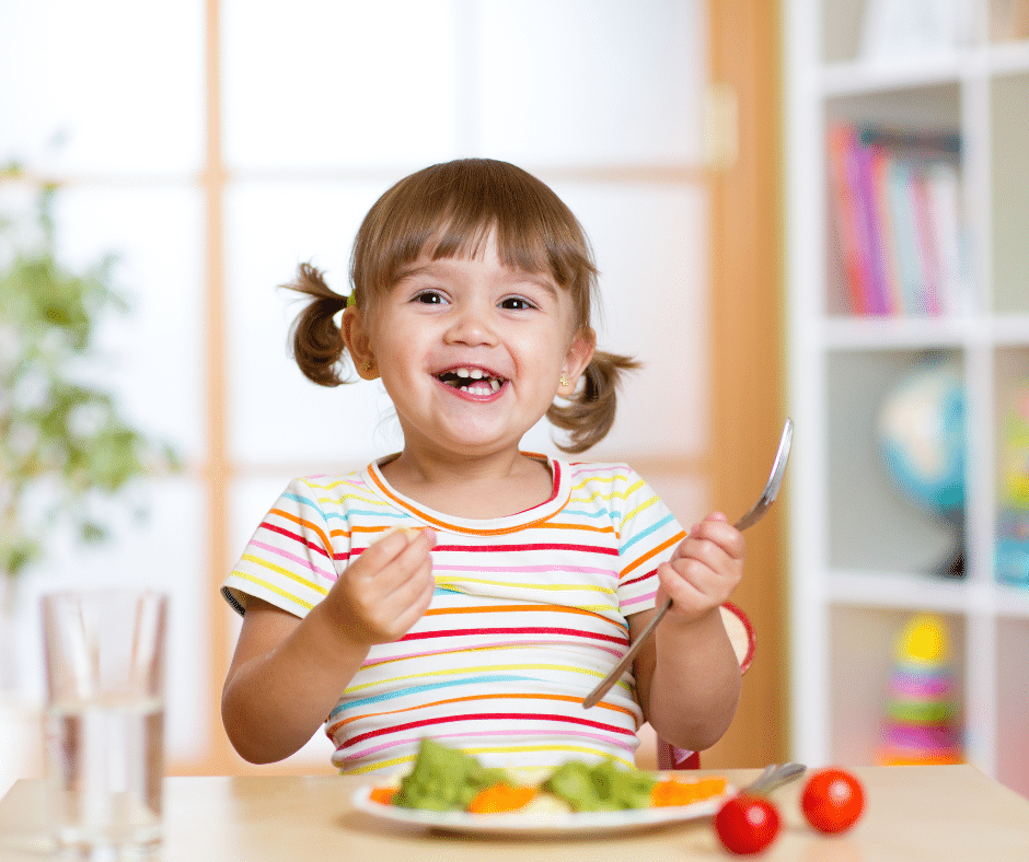 Toddler smiling and eating her veggies
