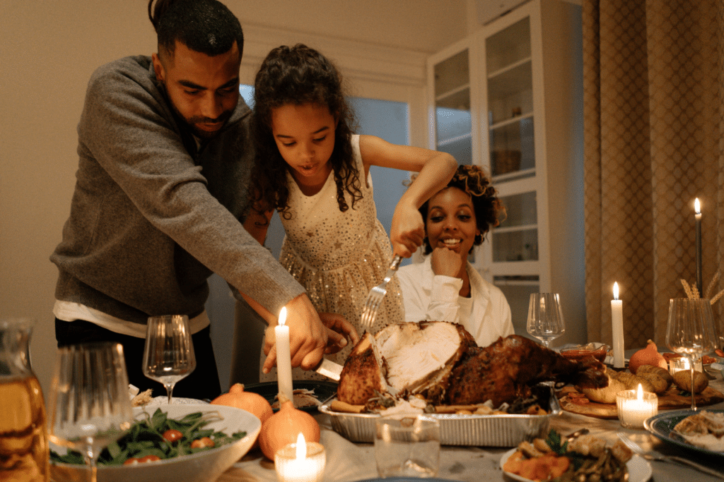 Family of three celebrating thanksgiving cutting the turkey