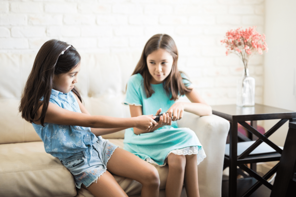 two young girls fighting over a remote