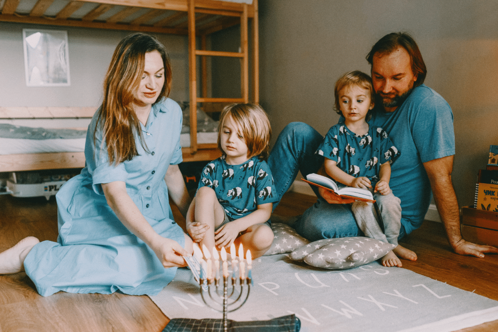 mom and dad with two young boys lighting the Channukah candles Hanukah