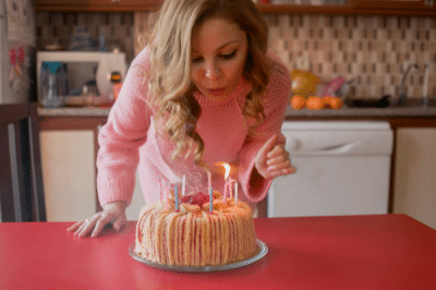 blonde woman blowing out candles on a makeshift birthday cake