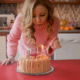 blonde woman blowing out candles on a makeshift birthday cake