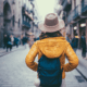 woman with backpack looking down a cobblestone street