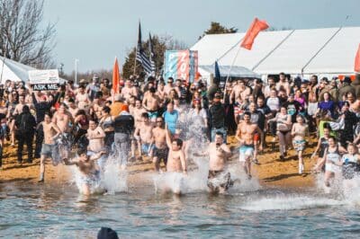 crowd of people running into the bay on the beach