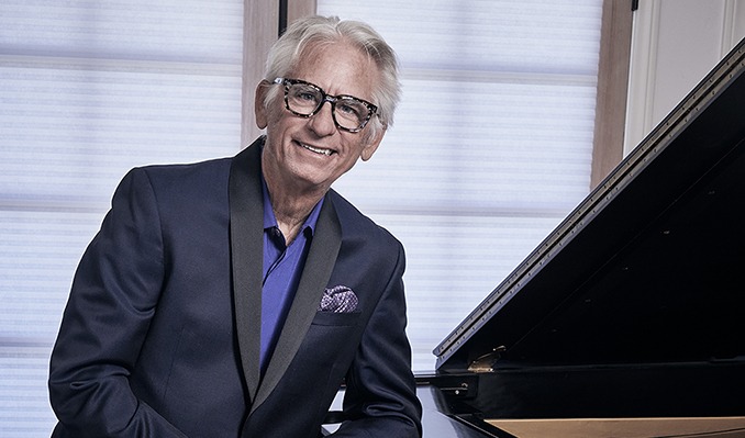 David Benoit sitting by piano