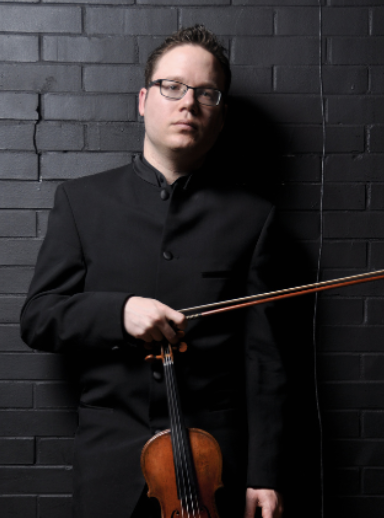 Man holding violin against black brick wall