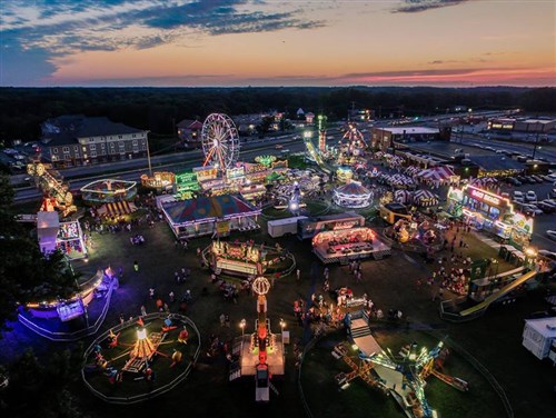 A photo of the carnival at Earleigh Heights later in the evening with a birds eye view of the different rides, games, and food stands.