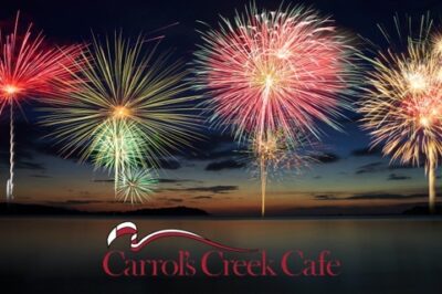 The words, "Carrol's Creek Cafe" with fireworks over the water behind it.