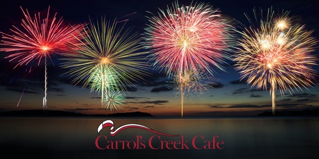 The words, "Carrol's Creek Cafe" with fireworks over the water behind it.
