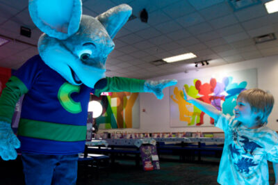 Chuck E Cheese giving high five to a boy