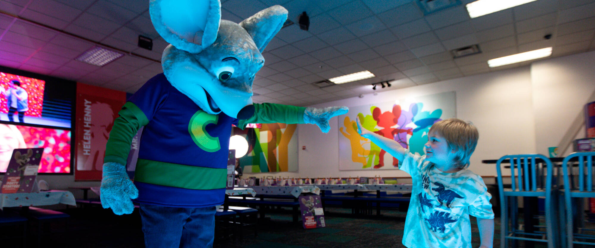 Chuck E Cheese giving high five to a boy