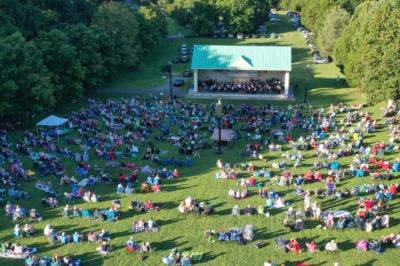 ariel view of group of people sitting on lawn watching an orchestra