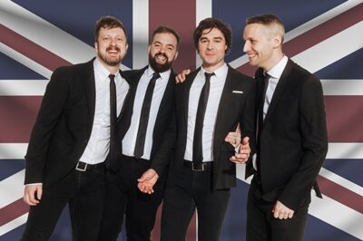 men in suits in front of British flag