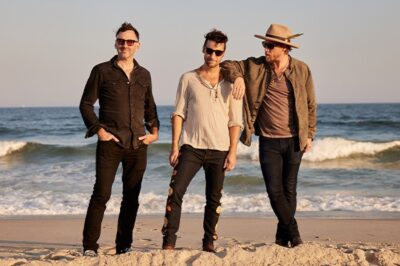 three men wearing casual clothes on the beach