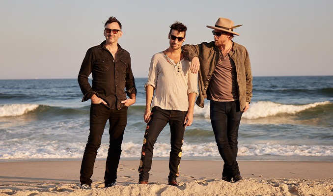 three men wearing casual clothes on the beach