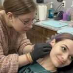 Hannah Swank piercing a clients ear.