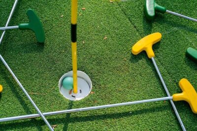 A bunch of putters and a golf ball on the green.